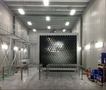 Interior of a stainless steel spray pickling and passivation bay featuring stainless steel fabrication equipment and organized workspaces, showcasing a hexagonal metal structure and bright overhead lighting for custom precision metal fabrication projects.